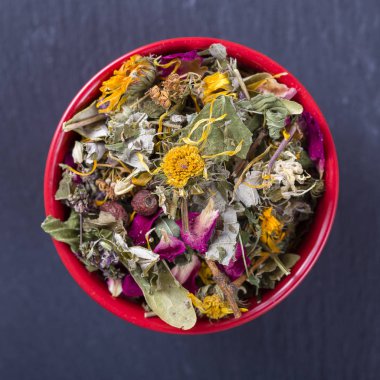 Farklı kuru otlar ve çiçekler kırmızı kapta, üstten görünüm, sağlıklı çay arka plan yapmak için Kapat