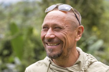 İnsanlar ve yaşam tarzı kavramı. Mutlu orta yaşlı tıraşsız adamla neşeli gülümseme yeşil doğa arka planı açık. Yetişkin erkek portre yakın çekim