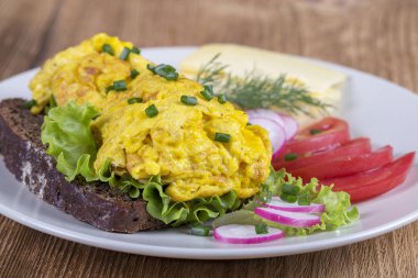 Bir parça kırmızı domates, peynir ve turp ahşap bir masa üzerinde siyah ekmek üzerinde yumurta omlet kapatın. Kahvaltı konsepti