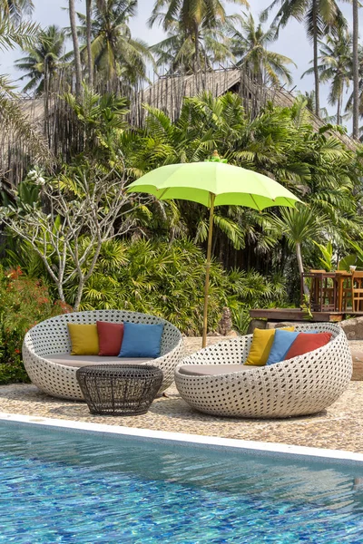 美丽的海滩与游泳池 椰子棕榈树 藤沙发床和雨伞在一个热带花园附近的海 — 图库照片