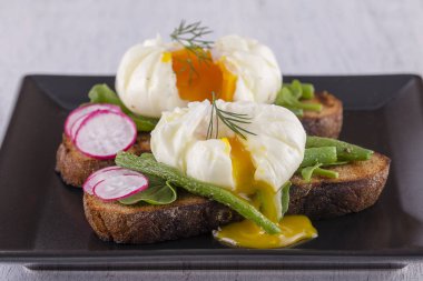 Bir parça ekmek kızarmış fasulye, turp, roka bir tabakta ile haşlanmış yumurta yakın çekim