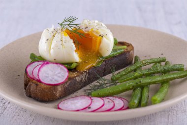 Bir parça ekmek kızarmış fasulye, turp, roka bir tabakta ile haşlanmış yumurta yakın çekim