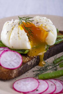 Bir parça ekmek kızarmış fasulye, turp, roka bir tabakta ile haşlanmış yumurta yakın çekim