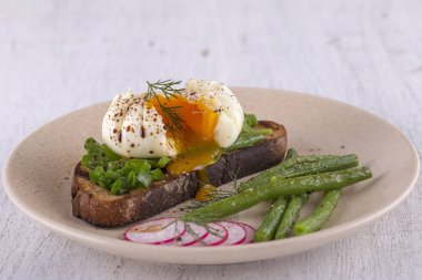 Bir parça ekmek kızarmış fasulye, turp, roka bir tabakta ile haşlanmış yumurta yakın çekim