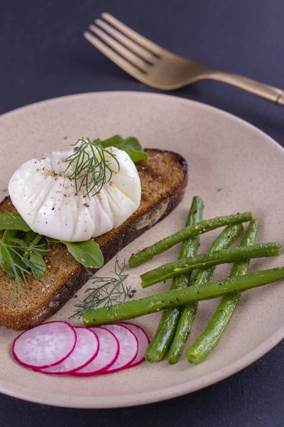 Bir parça ekmek kızarmış fasulye, turp, roka bir tabakta ile haşlanmış yumurta yakın çekim