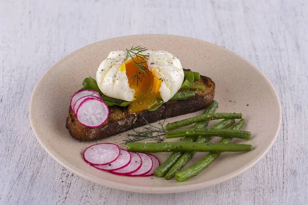 把鸡蛋放在一块面包上 用油炸青豆 萝卜和芝麻菜放在盘子上 — 图库照片