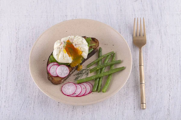 Bir parça ekmek kızarmış fasulye, turp, roka bir tabakta ile haşlanmış yumurta yakın çekim