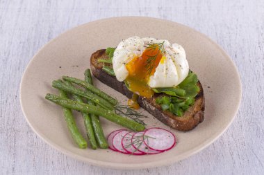 Bir parça ekmek kızarmış fasulye, turp, roka bir tabakta ile haşlanmış yumurta yakın çekim