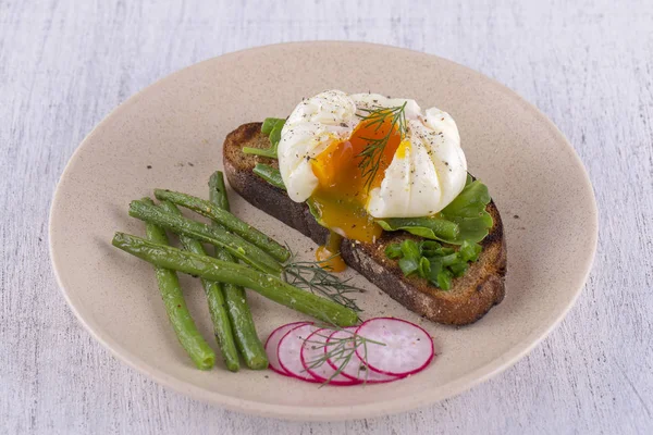 Bir parça ekmek kızarmış fasulye, turp, roka bir tabakta ile haşlanmış yumurta yakın çekim