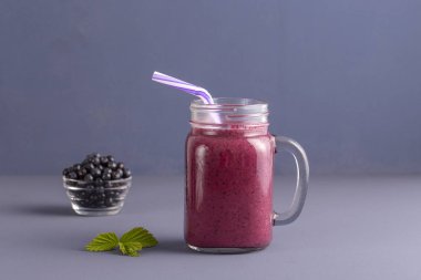 Sağlıklı beslenme, gıda, diyet ve vejetaryen kavramı - yaban mersini ve muz cam kupa, güler yüzlü kapatın. Taze yaban mersini ve gri arka plan üzerine suyu