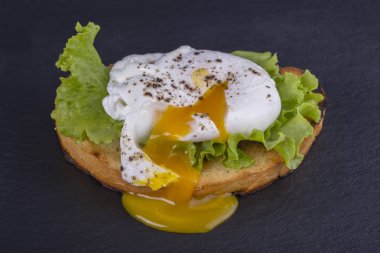 Bir parça ekmek üzerinde çılbır siyah arduvaz zemin, yeşil salata yaprakları ile yakın çekim