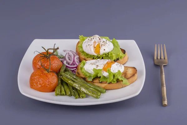 把鸡蛋放在一块面包上 用油炸青豆 西红柿和芝麻菜放在盘子上 — 图库照片
