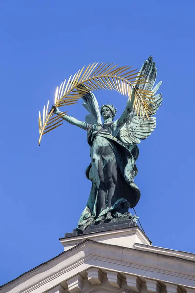 金のヤシの枝とウクライナのリヴィウのオペラやバレエ劇場の屋根の上に翼を持つブロンズ彫刻の天才 青空の背景 — ストック写真