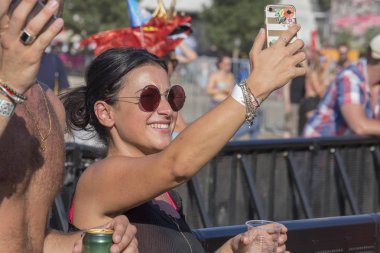 Budapeşte, Macaristan - 15 Ağustos 2017: Bilinmeyen kızlar ve çocuklar olduğunu kültür katılımcılar ve müzik festivali Sziget. Güzel kız Sziget Festivali'nde telefonda bir fotoğraf yapmak