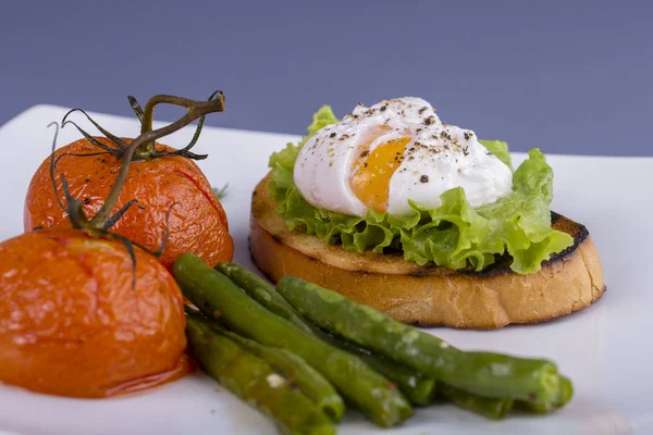 튀긴된 토마토와 Arugula 접시에 조각에 데친된 달걀을 닫습니다 — 스톡 사진