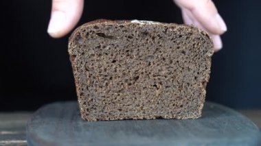 Kahverengi ekmek iki dilim ahşap tahta kesme. Bütün tahıl ekmeği bir bıçak ile kesmek. Karanlık ekmek, sağlıklı yaşam yakın çekim. 