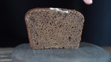 Kahverengi ekmek iki dilim ahşap tahta kesme. Bütün tahıl ekmeği bir bıçak ile kesmek. Karanlık ekmek, sağlıklı yaşam yakın çekim. 