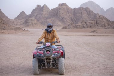 Bir Atv bir adam portresi. Sharm El Sheikh, Mısır yakınlarında çölde safari Quad bisiklet. Güçlü hızlı off-road dört tekerlekten çekiş ATV, motosiklet kumlu çölde karşı yüksek dağlar ralli.