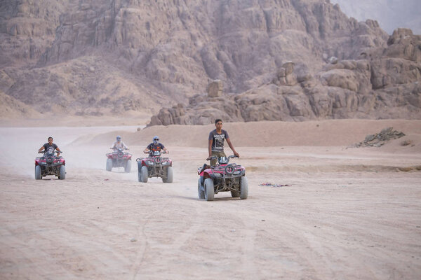 SHARM EL-SHEIKH, EGYPT - MAY 19, 2018 : Quad bikes safari in desert near Sharm El Sheikh, Egypt. Powerful fast off-road four-wheel drive ATVs, motorcycles in sandy desert, rally against high mountains