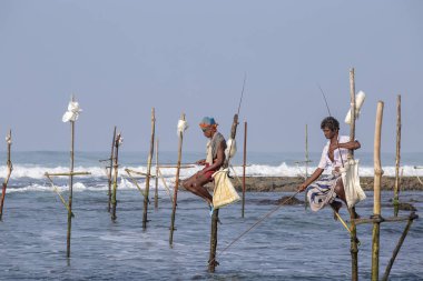 Koggala, Sri Lanka - 9 Kasım 2014: Yerel balıkçılar ahşap stilts üzerinde oturmak ve okyanusta balık yakalamak. Bu tür balık tutma için Güney Sri Lanka Hint Okyanusu'nda geleneksel