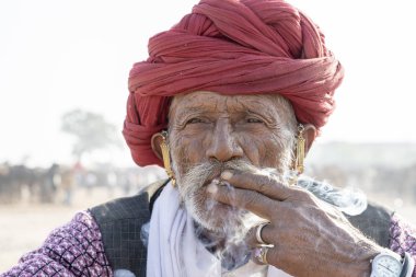 PUSHKAR, INDIA - 16 Kasım 2018: Hindistan 'ın kutsal şehri Pushkar, Rajasthan yakınlarındaki Pushkar Camel Mela sırasında çöldeki Hintli adam. Bu fuar dünyanın en büyük deve ticaret fuarı..