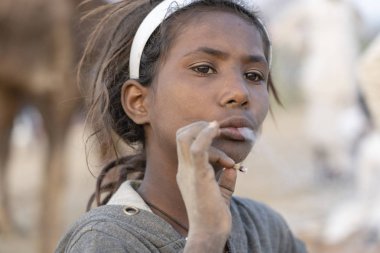 PUSHKAR, INDIA - 14 Kasım 2018: Çölde sigara içen Hintli genç kız Thar zamanında Pushkar Camel Mela kutsal şehir Pushkar, Rajasthan, Hindistan, yakın plan portresi