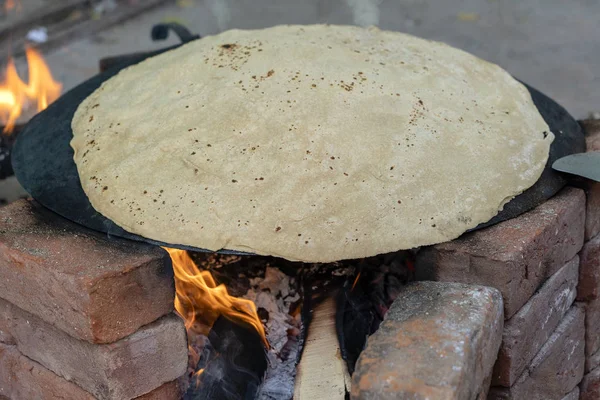 Indian woman cooking traditional indian bread, big chapati cooking on open fire in Udaipur, Rajasthan, India. Close up
