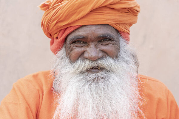 РИШИКЕШ, Индия - 05 ноября 2018 года: Неопознанный индуистский святой человек садху, сидит на гате возле реки Ганг в Ришикеше, Индия, крупным планом