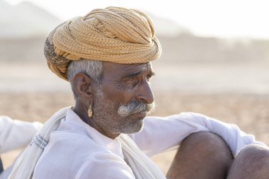 PUSHKAR, INDIA - 12 Kasım 2018: Hindistan 'ın kutsal şehri Pushkar, Rajasthan yakınlarındaki Pushkar Camel Mela sırasında çöldeki Hintli adam. Bu fuar dünyanın en büyük deve ticaret fuarı..