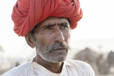 PUSHKAR, INDIA - 14 Kasım 2018: Hindistan 'ın kutsal şehri Pushkar, Rajasthan yakınlarındaki Pushkar Camel Mela sırasında çöldeki Hintli adam. Bu fuar dünyanın en büyük deve ticaret fuarı..