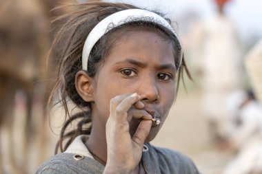 PUSHKAR, INDIA - 14 Kasım 2018: Çölde sigara içen Hintli genç kız Thar zamanında Pushkar Camel Mela kutsal şehir Pushkar, Rajasthan, Hindistan, yakın plan portresi