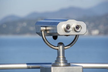 Public binocular on sea shore, close up. Coin operated binocular viewer on blurred background of sunset and sea. Batumi, Georgia clipart