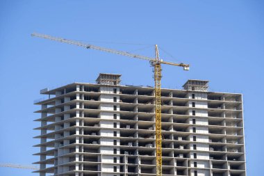 Yüksek katlı bir vinç ile bina inşaatı. Bina inşaat kalıp kullanarak. İnşaat Vinç ve mavi gökyüzü karşı bina.