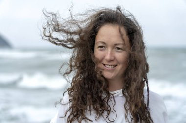 Arka tarafa başını sallayarak ve saç rüzgarda çırpınan deniz genç kadın. Deniz kıyısında şirin esmer kız. Güzel kadın bir rüzgar, özgürlük hissi sahiptir