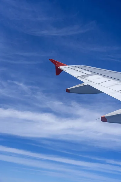 Wing of airplane flying above the white clouds in the blue sky . The theme of tourism and travel