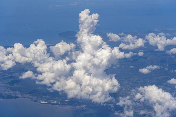 Schöne Aussicht aus dem Flugzeugfenster über weiße Wolken, Meeresoberfläche und Insel. Naturpanorama mit Wolken, Wasseroberfläche von Meer und Land — Stockfoto