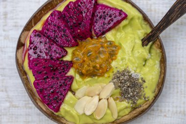 Dragon meyve ile Hindistan cevizi kase yeşil avokado Smoothie, tutku meyve, badem gevreği, Hindistan cevizi cips ve kahvaltı için Chia tohumları, yakın. Sağlıklı yeme kavramı, Superfood