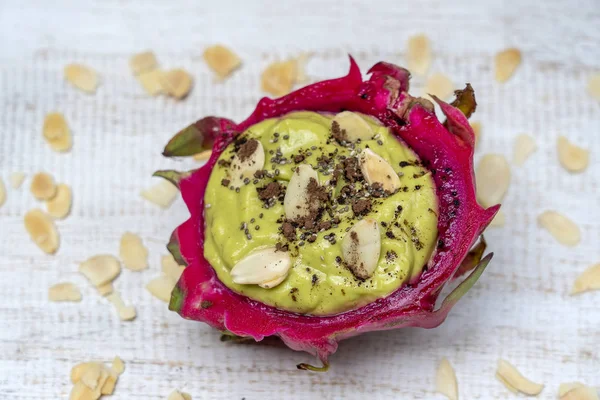 Batido de aguacate verde en piel de fruta de dragón con hojuelas de almendras y semillas de chía para el desayuno, de cerca. El concepto de alimentación saludable, superalimentos — Foto de Stock