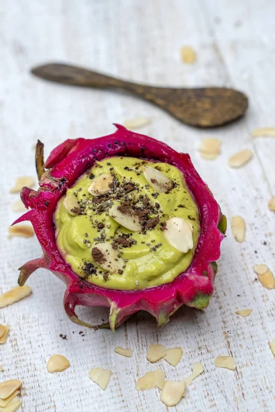 Green avocado smoothie in dragon fruit skin with almond flakes and chia seeds for breakfast , close up. The concept of healthy eating, superfood — Stock Photo, Image