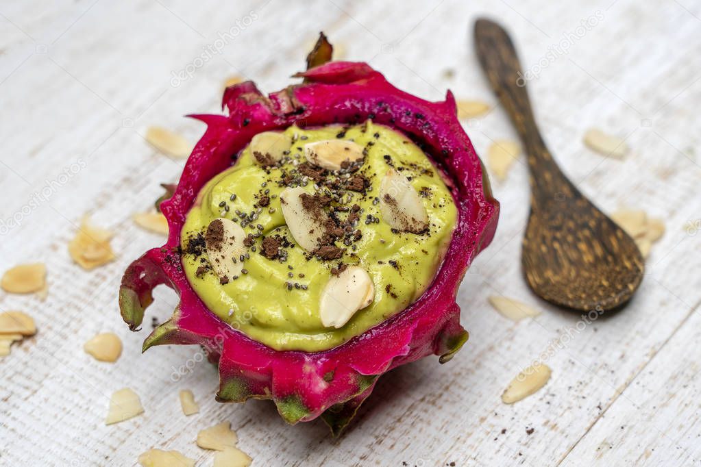 Green avocado smoothie in dragon fruit skin with almond flakes and chia seeds for breakfast , close up. The concept of healthy eating, superfood