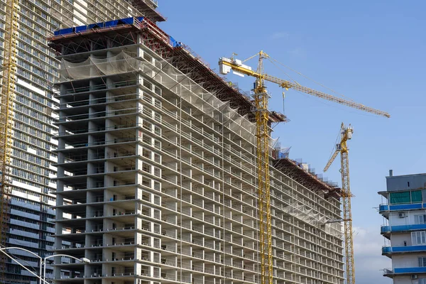 Construção de um edifício alto com guindaste. O guindaste de construção e o edifício contra o céu azul . — Fotografia de Stock