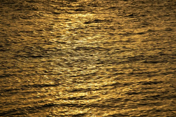 Reflexão do pôr do sol brilha em pequenas ondulações de onda de água do mar — Fotografia de Stock