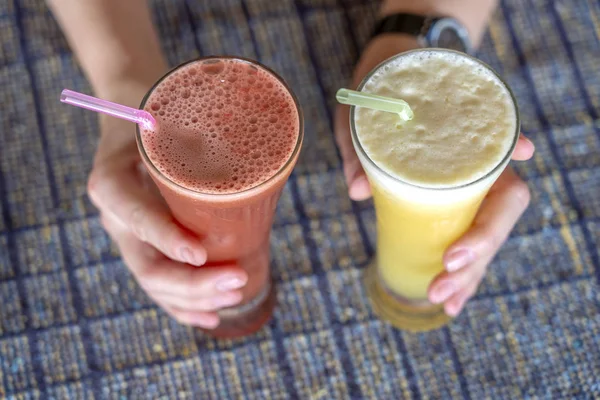 Mãos de mulher segurando dois copos com abacaxi e melancia suco fresco, de perto — Fotografia de Stock