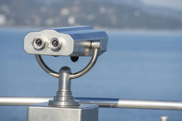 Binocular público na costa do mar, de perto. Moeda operado visualizador binocular no fundo turvo do pôr do sol e do mar — Fotografia de Stock