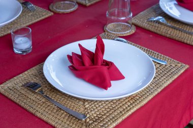 Restoranda çatal, kaşık, beyaz plaka ve kırmızı peçete ile zarif masa ayarı. Düzenlenmiş gümüş ve peçeteler ile güzel yemek masası seti