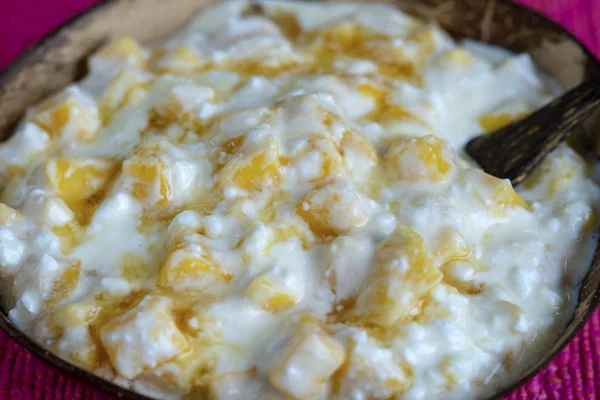 Scheiben reife süße gelbe Mango-Früchte mit weißem Quark, Honig und saurer Sahne in Kokosnussschale, Nahaufnahme — Stockfoto