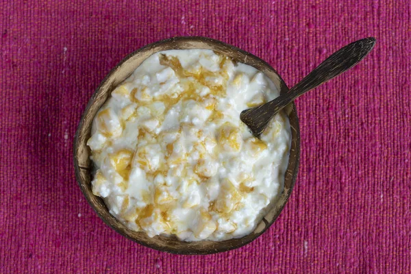 Slices of ripe sweet yellow mango fruit with white cottage cheese, honey and sour cream in coconut bowl , closeup — Stock Photo, Image