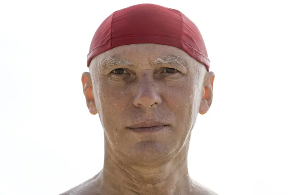 Idős férfi egy piros kalapot a strandon, közel a tengervíz — Stock Fotó