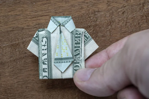 Chemise en origami faite de billets de banque en dollars et main sur fond en bois. Gros plan. T-shirt Dollar bill — Photo