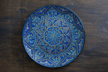Mavi ve altın rengi nde dekoratif seramik plaka, ahşap arka plan üzerine boyanmış plaka, closeup. Akrilik boyalar ile boyanmış dekoratif porselen plaka, el işi